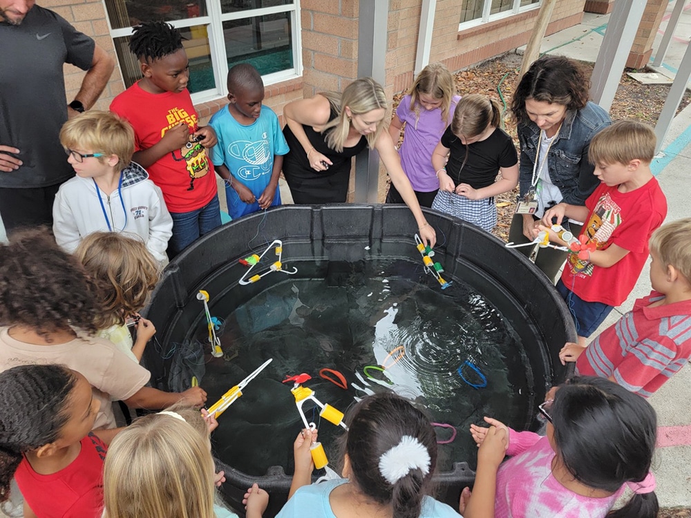 Children and adults gathered around a black pool with toys.